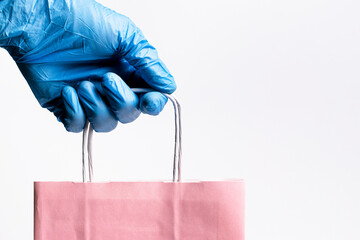 Craft package in hand. Safe delivery. Gloved hands hold a pink paper bag.