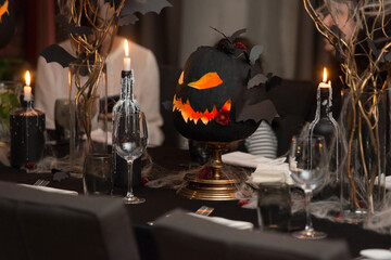 Table set for Halloween dinner. Served holiday table with candles and pumpkin