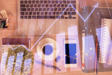 Double exposure of financial graph hologram over desktop with phone. Top view. Mobile trade platform concept.