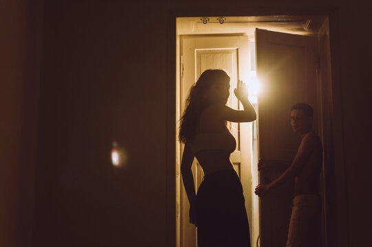 Silhouette of girl and boy standing near luminous door