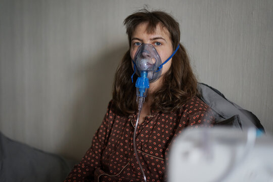 A young sick woman doing inhalation and looking at camera at home
