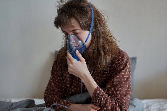 A sick woman at home alone in bed doing inhalation