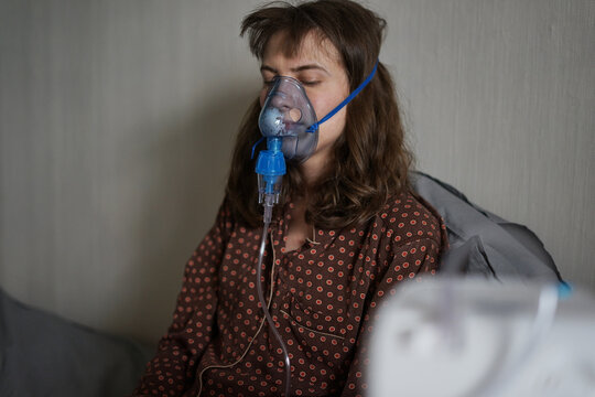 A sick young woman doing inhalation at home