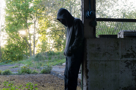 A hooded, masked figure standing in a ruined building.