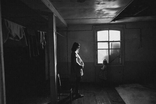 mother and daughter stand in front of a window in an old room