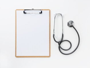 A clipboard and stethoscope with white paper on it on a white background