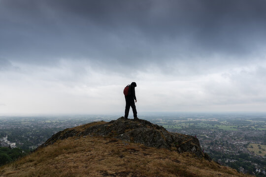 A hiker on top of a hill, looking down. Malvern Hills, UK.