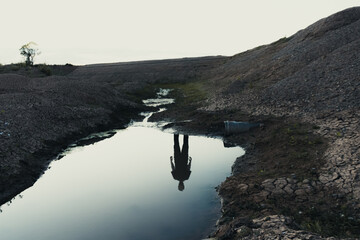 A haunted landscape of a ghostly reflection of a figure in water