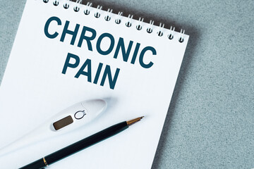 The text is a chronic pain. Top view written on white paper pad on the desktop. Medical concept.