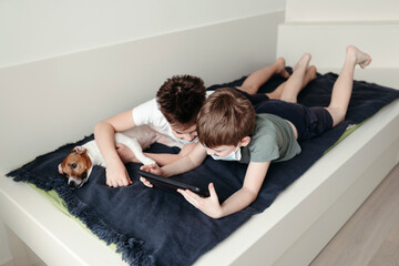 Young brothers in protective medical masks at the game tablet.