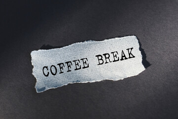 Coffee break - text on torn paper on dark desk in sunlight.