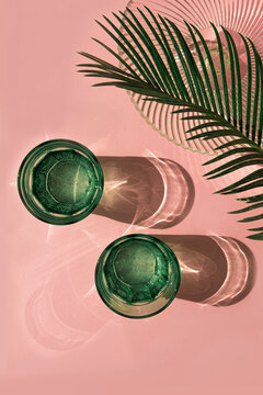 Studio shot of palm leaves, glass bowl and two glasses of carbonated water