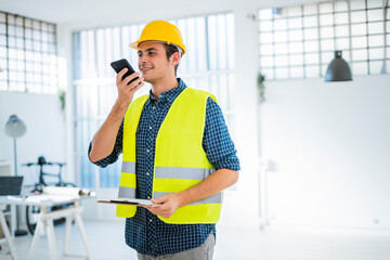 Smiling young man talking on mobile phone while standing at office under construction