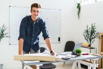 Smiling man leaning on desk while standing at office
