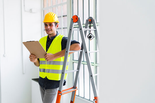 Smiling architect leaning while standing by ladder at office under construction