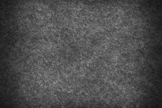 Black grey  felt material with dark vignette. Surface of felted fabric texture abstract background in black gray color. 