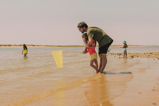 Father with daughter fishing crab in sea against clear sky