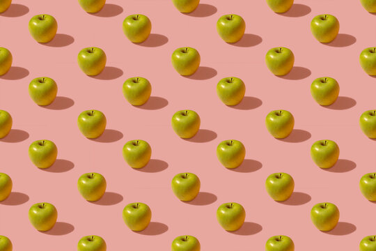 Pattern of green apples against pink background