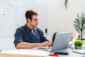 Architect working on laptop while sitting by table at office