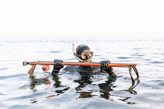 Man hunting with harpoon in sea against clear sky
