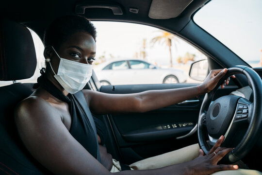 Woman with protective face mask driving car