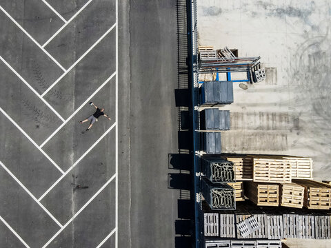 Drone view of man lying on back in empty parking lot