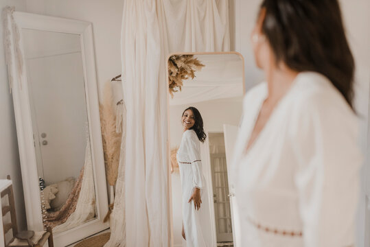 Young bride looking in mirror while standing at home