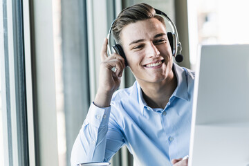 Close-up of smiling male customer representative talking over headset in office