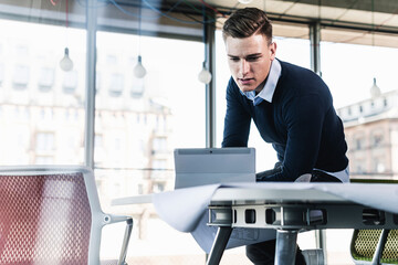 Male professional working over digital tablet while sitting on desk in office