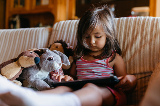 Girl using digital tablet while sitting on sofa at home