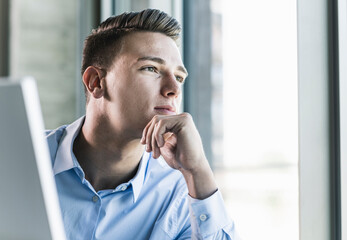 Close-up of thoughtful businessman with hand on chin sitting in office
