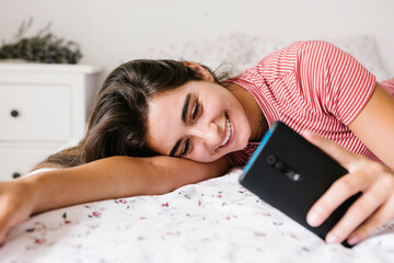 Smiling young woman text messaging on smart phone