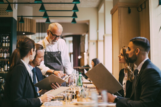 Waiter showing menu to business people in restaurant