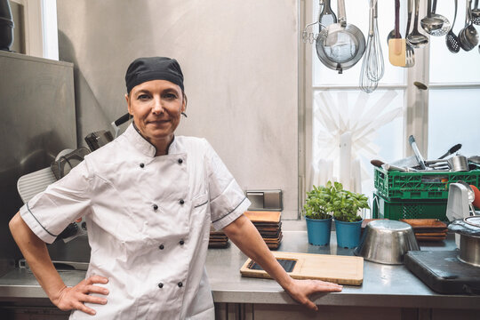 Portrait of confident mature chef with hand on hip in commercial kitchen