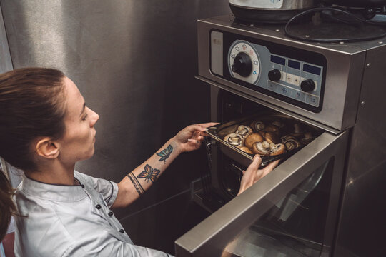 High angle view of female chef baking mushrooms in oven