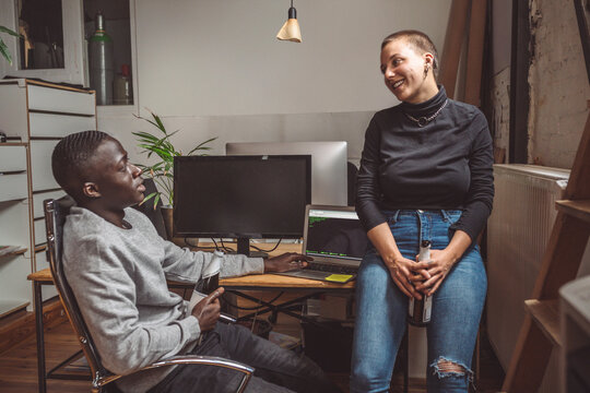 Smiling computer programmers talking to coworker at workplace