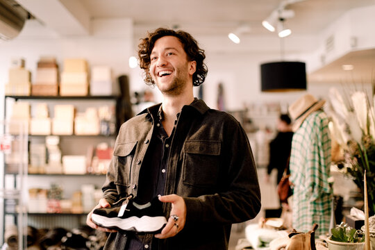 Happy male customer looking away while buying shoe at retail store