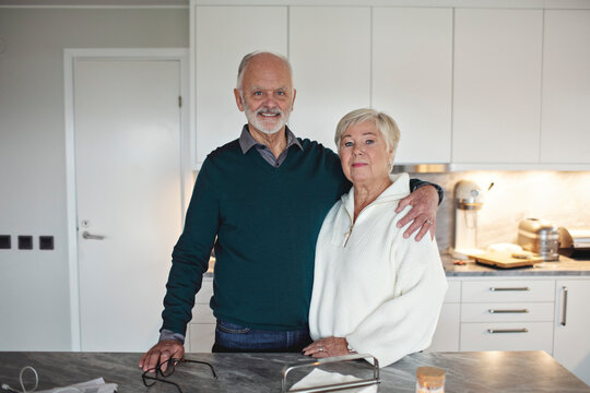 Portrait of senior couple standing by kitchen island at home