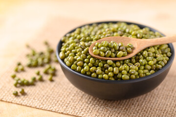 Mung bean in a bowl and spoon on wooden background