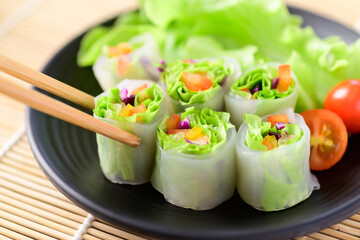 Colorful fresh vegetables salad spring roll eating with chopsticks, Healthy vegan food