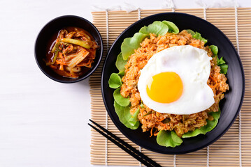 Kimchi fried rice with fried egg on top and fresh kimchi cabbage, Korean food, Top view