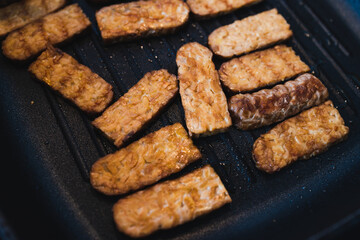 simple food ingredients, grilled tempeh getting cooked on griddle pan on the stove