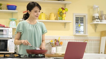 Fototapeta na wymiar パソコンを見ながら料理をする女性