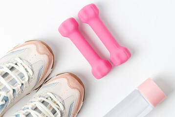 Sneakers, dumbbells and bottle of water on white background, view from above