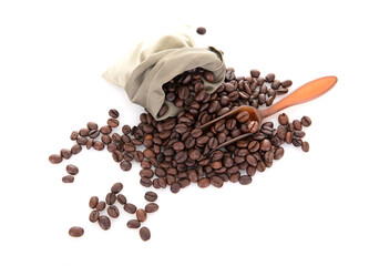 Looking down on coffee beans poured out from a small bag and a spoon on a white background