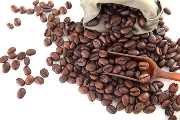 Closeup of coffee beans and a spoon scattered from the bag on white background