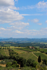 Fototapeta na wymiar Aerial view of San Gimignano, Tuscany, Italy. Vineyards and farms, blue sky and scattered clouds. No people.