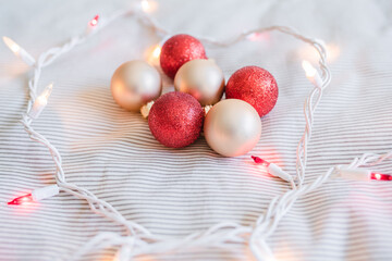 littered Red and Cream colored Christmas tree ornaments on the bed around red and white Christmas lights. White and airy feeling.  - 388909604