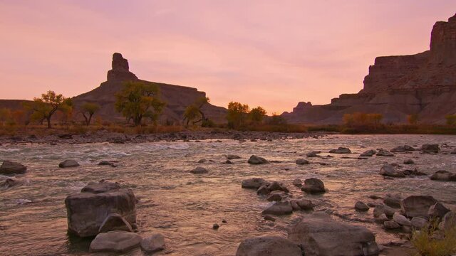 Green River flowing in slow motion as the landscape glows in Utah as the sun lights up the sky.