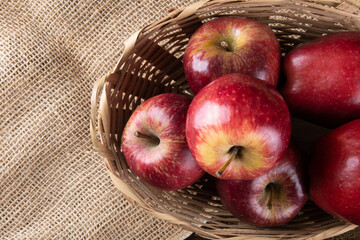 Red apples in basket with wooden background. Top view.